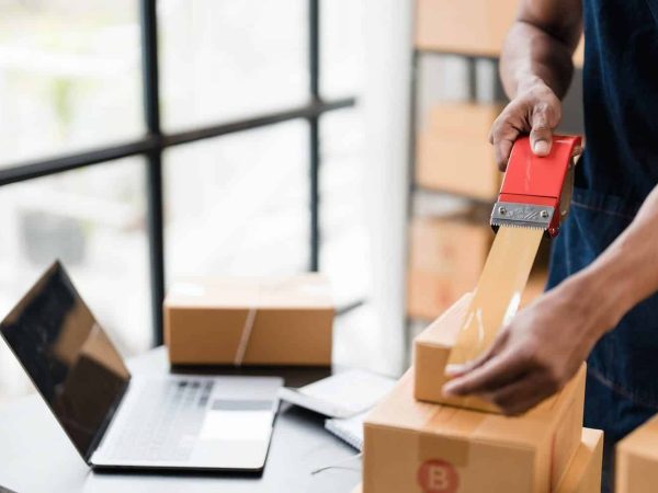 Photo of young entrepreneur man packing he goods while sitting in table comfortable sitting room as